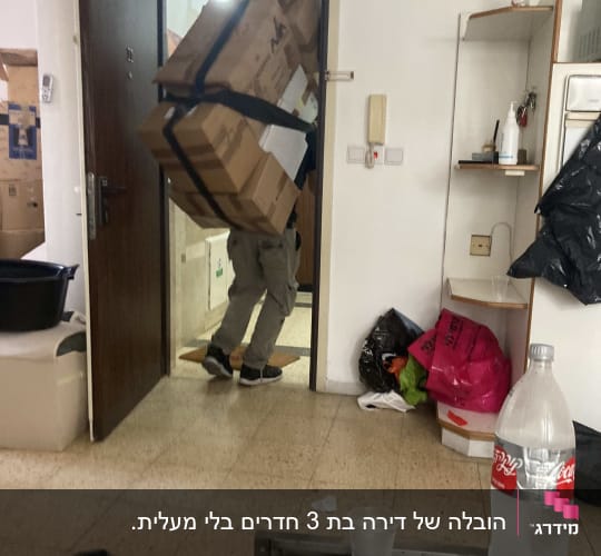 אדם נושא קופסאות גדולות דרך דלת פתוחה